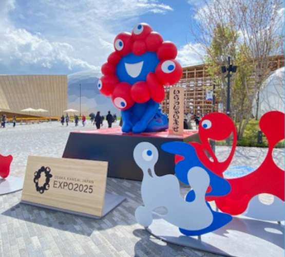 大阪万博2025年の公式キャラクター　ミャクミャクがお辞儀をしてる像の写真　青空