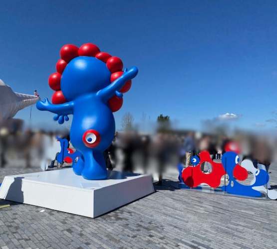 大阪万博2025年の公式キャラクター　ミャクミャクが両手を広げている像の後ろからの写真　青空